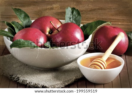 Bowl with honey and red apples on the plate. For this photo applied aging effects. 