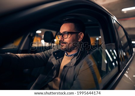 Side view portrait of a handsome stylish man driving car at night Royalty-Free Stock Photo #1995644174