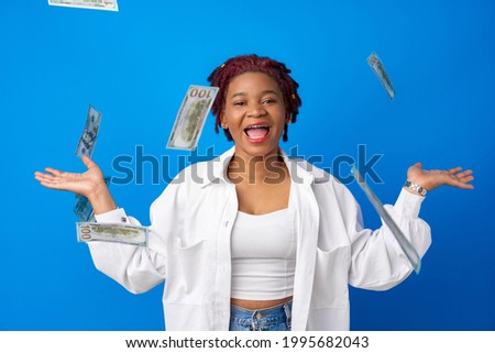 Happy smiling afro american woman throwing money against blue background