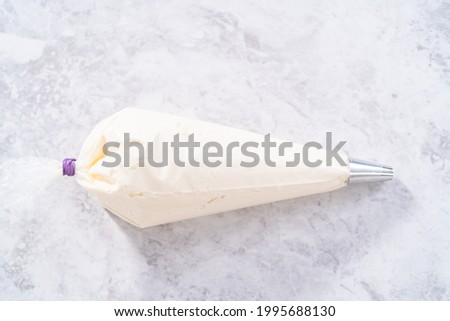 White buttercream frosting in a piping bag with a metal tip.