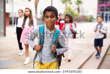 Portrait of African american tweenager walking outside school building on autumn day, going to lessons.