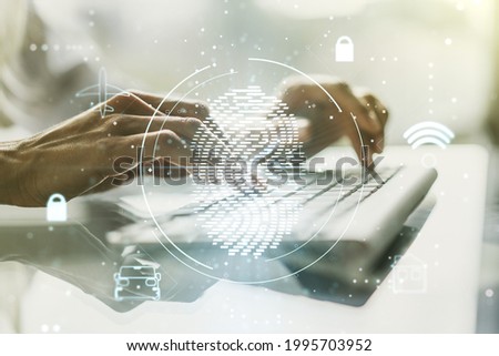 Double exposure of abstract creative fingerprint hologram with hands typing on laptop on background, protection of personal information concept