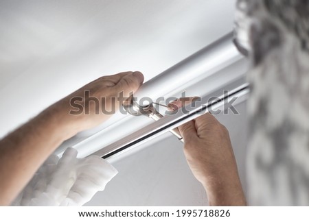 Installation of a curtain rod with curtains over the window. Hang curtains, home renovation and apartment decor. selective focus Royalty-Free Stock Photo #1995718826