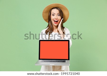 Traveler shock tourist woman in clothes hat camera hold laptop pc computer blank screen workspace hold face isolated on green background Passenger travel abroad on weekends. Air flight journey concept