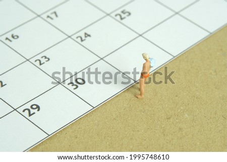 Miniature people toy figure photography. Travel plan schedule concept, men standing in front of calendar. Image photo