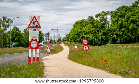 Road work sign under construction. Cars not allowed. Caution and safety symbol. Red and white triangle safety sign beside the path.