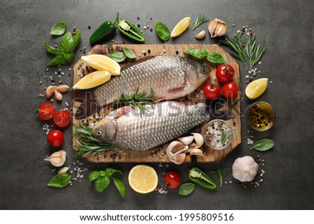 Fresh raw crucian carps and ingredients on grey table, flat lay. River fish Royalty-Free Stock Photo #1995809516