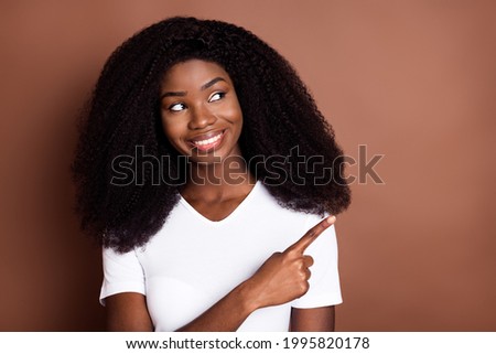 Portrait of attractive cheerful wavy-haired girl demonstrating copy space ad solution isolated over brown color background