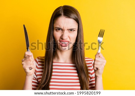 Portrait of attractive angry girl holding cutlery fast food meal snack isolated over bright yellow color background Royalty-Free Stock Photo #1995820199