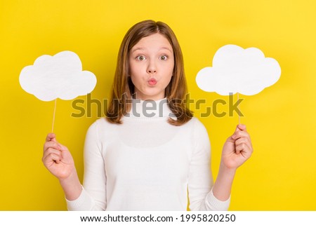 Photo of positive cute pretty small girl hold hands clouds send air kiss isolated on shine yellow color background