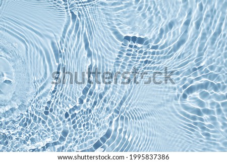 Water spills on a light blue background. Aqua waves on green background. Light and shadows. Natural sunlight and shade. Beautiful bursts and glare. Summer mood. Minimal style.