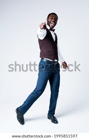 Full-length photo. Cheerful african american businessman dancing and showing his finger to the camera