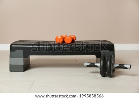 Step platform, dumbbells and abdominal wheel indoors. Sports equipment