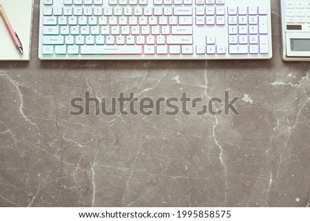 Modern RGB keyboard and stationery on grey table, flat lay. Space for text
