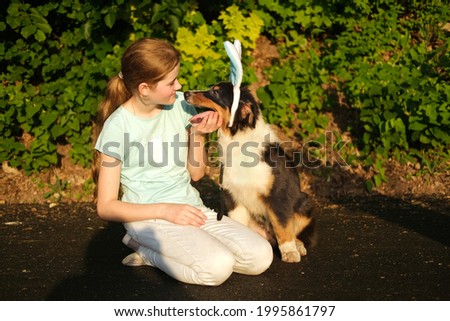 Teenage girl with funny Australian shepherd puppy dog in bunny ears.
