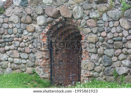 opening in the stone wall is closed with a latticework. Stock photography