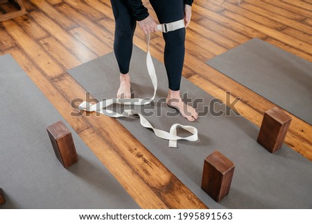 Cropped view of woman stretching her leg with strap in yoga studio