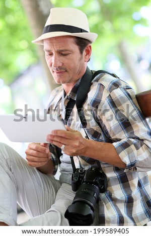 Photo reporter in town using digital tablet