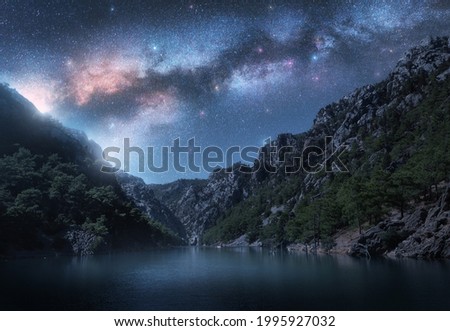Milky Way and stars over beautiful mountain canyon and blue sea at night in summer. Colorful landscape. Bright starry sky with Milky Way, rocks, trees, fog over the lake. Galaxy. Nature and space	