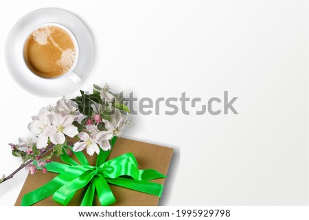 Coffee mug with a bouquet of flowers and gift box on desk
