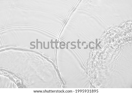 Desaturated transparent clear calm water surface texture with ripples, splashes Abstract nature background. White-grey water waves in sunlight Copy space Cosmetic moisturizer micellar toner emulsion Royalty-Free Stock Photo #1995931895