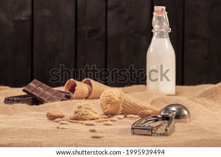 Delicious nougat ice cream cone surrounded by out of focus ice cream scoop, chocolate and bottle of milk: Selective focus  Ice cream concept 