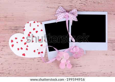 Blank old photos and decorative heart on color wooden background