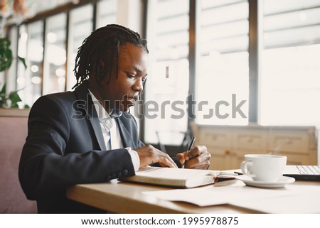 Handsome african man in a black suit in a cafe