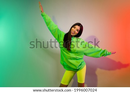 Portrait of attractive cheerful girl dancing like plane having fun isolated over multicolor vivid neon light background