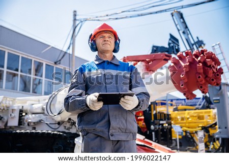 Miner operator in helmet with tablet computer control drilling machine in coal mine. Concept smart industrial mining.