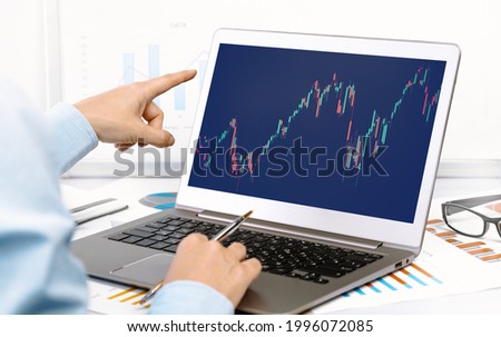 Stock exchange trade and forex financial concept. Laptop with graphs female hands pointing at. office desk. Distant learning or broker working from home office, online courses concept.