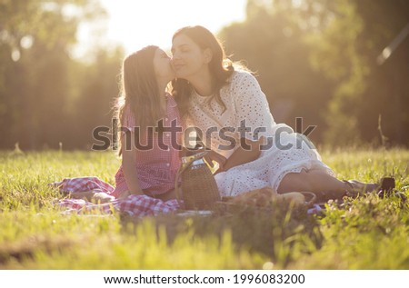 Mother and daughter in the park. Daughter kissing her mom.