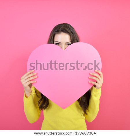 Love and valentines day woman holding heart and smiling over pink background. Beautiful woman in love. 