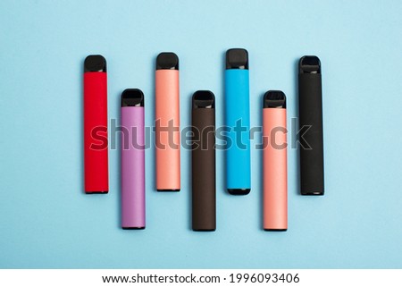 Set of colorful disposable electronic cigarettes on a blue background. The concept of modern smoking. Top view Royalty-Free Stock Photo #1996093406