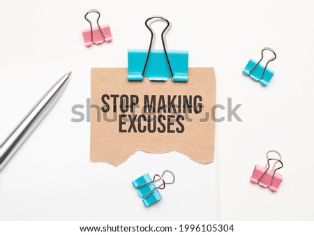 Business and finance concept. On a white background lies a notebook, a pen, clothespins and cardboard with the inscription - STOP MAKING EXCUSES