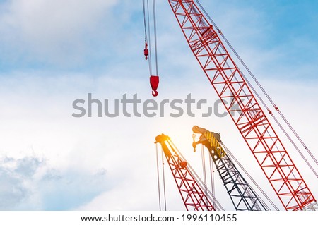 Crawler crane against blue sky and white clouds. Real estate industry. Red crawler crane use reel lift up equipment in construction site. Crane for rent. Crane dealership for construction business. Royalty-Free Stock Photo #1996110455