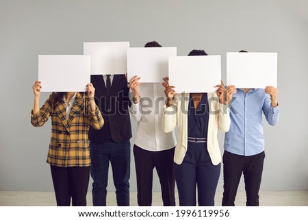 Group of unrecognizable young multiracial people covering faces hiding behind blank mockup signs. Team of anonymous multiethnic office workers holding empty white sheets of paper Royalty-Free Stock Photo #1996119956