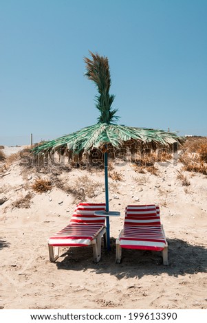 Green straw beach umbrella with sun beds on a beautiful beach.