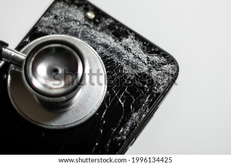 black mobile phone with broken screen and stethoscope,selective focus,isolated on white background.Cell phone crash From the high point of the screen cracked.