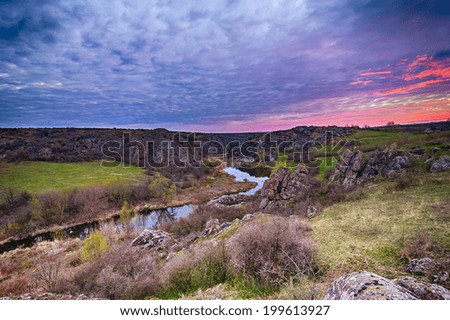 Sunrise at canyon with river, hills and dramatic sky with reflection