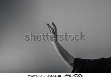 The hand of a young girl is raised up. Dramatic light. Black and white photo.