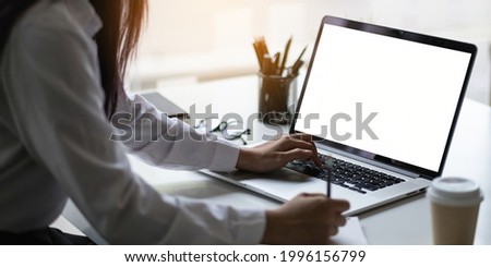 Mockup image of a laptop computer with white blank screen on wooden desk.