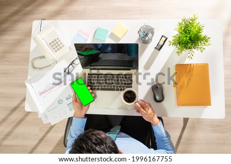 overhead view of man work and use green screen smartphone with laptop 