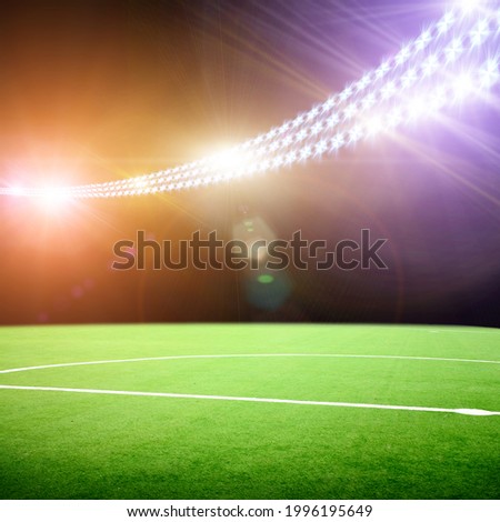 Center of a green football field on a stadium with bright floodlight lights and flashes at night