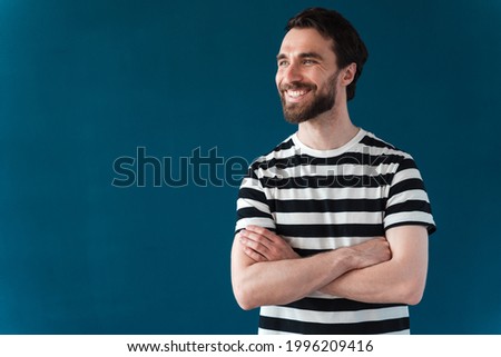 Attractive man with a beard crossed his arms over his chest. Positive man posing on a blue background
