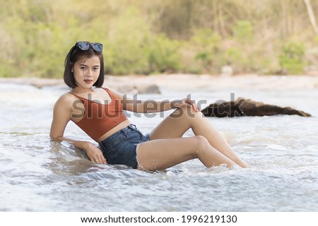 A woman short hairs in short pants and waistcoat on nature water and waterfall , she enjoy and relax time in weekends