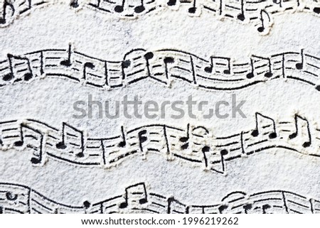 Musical notes pattern printed on white flour sand, powder on dark table. Natural, organic background. Abstract grainy texture. Minimalist monochrome wallpaper. Music festival banner template.