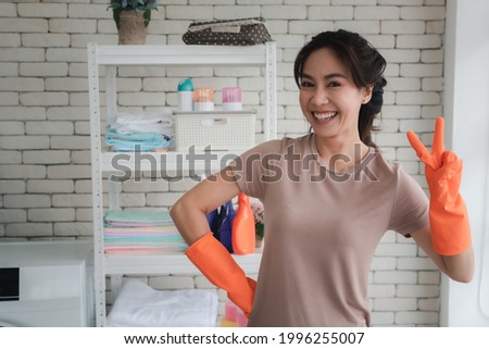 Housewife with cleaning supplies in orange rubber gloves