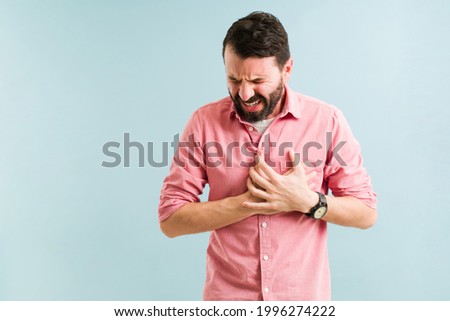 Hispanic man in his 30s having a heart attack and suffering from chest pain. Middle age man with a cardiovascular disease  Royalty-Free Stock Photo #1996274222