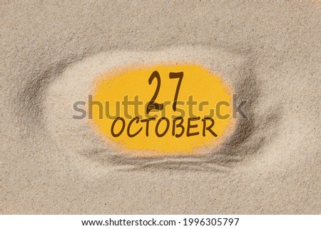 October 27. 27th day of the month, calendar date. Hole in sand. Yellow background is visible through hole. Autumn month, day of the year concept.